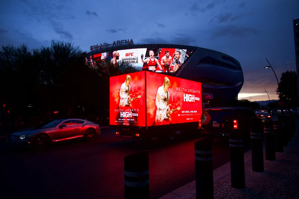 LED mobile billboard trucks displaying digital advertisements at a major venue at night